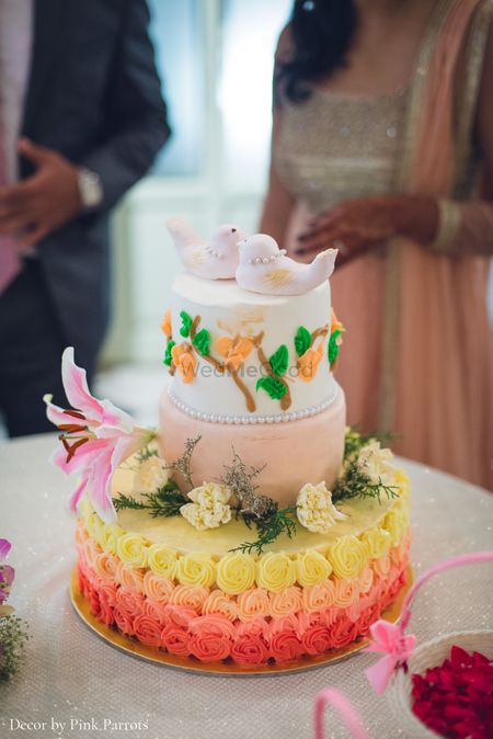 White and orange ombre wedding cake with birds as cake topper