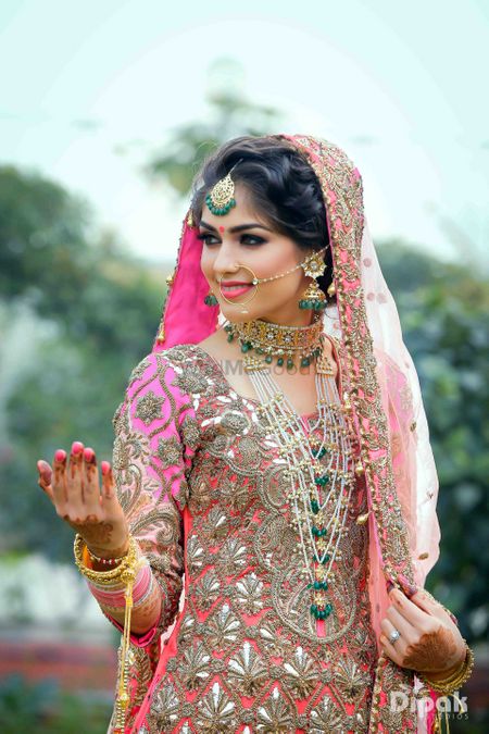 Bride wearing layered jewellery with green beads with choker and satlada