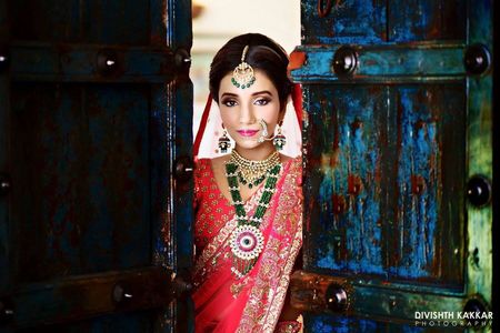 Bridal portrait in red saree and green jewellery