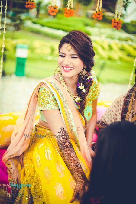 Mehendi bridal portrait with bride in yellow getting mehendi put