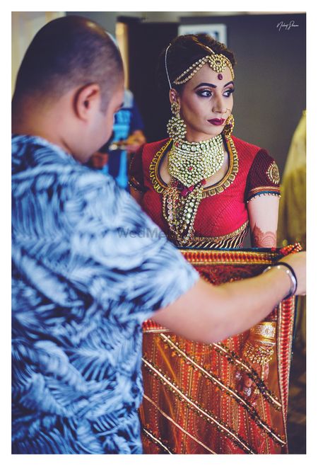 Candid portrait of bride while getting dupatta pinned