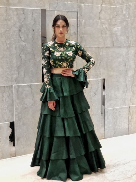 Beautiful bottle green lehenga with bell sleeved blouse and floral print along with a layered lehenga skirt