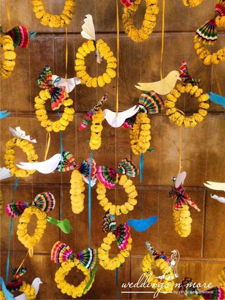 Mehendi decor idea with hanging genda phool rings and bird cutouts