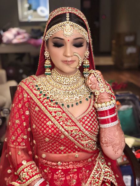 Photo of Pretty bride wearing red lehenga with gold jewellery for wedding