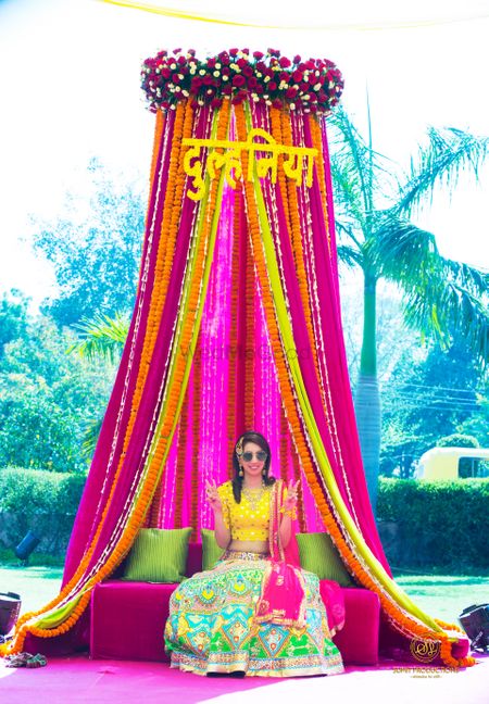 Mehendi decor idea with bright pink and yellow theme and bridal seat