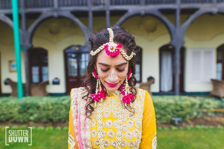 Bride in bright pink and white floral jewellery on mehendi
