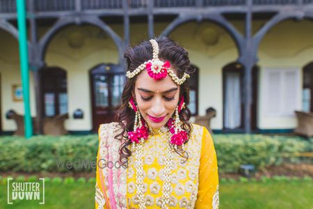 Bride in bright pink and white floral jewellery on mehendi