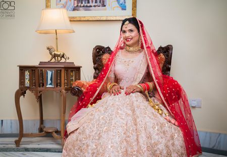 Monotone bridal pink lehenga with red dupatta over the head