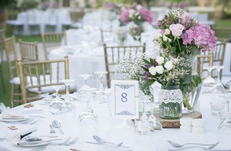 Gorgeous table setting with white and lavender flowers in glass jars