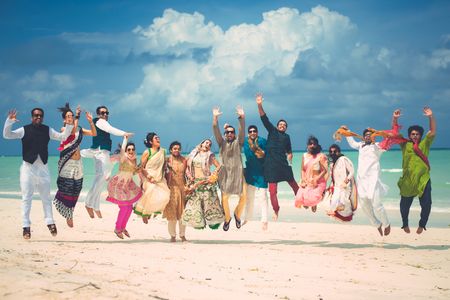 Photo of Bride and groom with friends jumping in the air shot