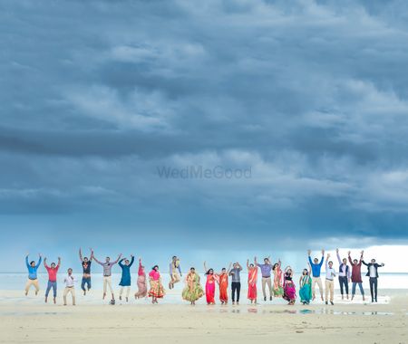Beach wedding with bride and groom and friends jumping