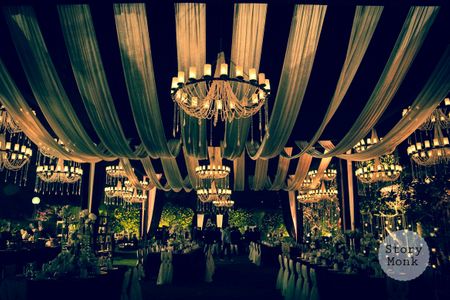 Night decor with white draped ceiling and candle lit chandeliers