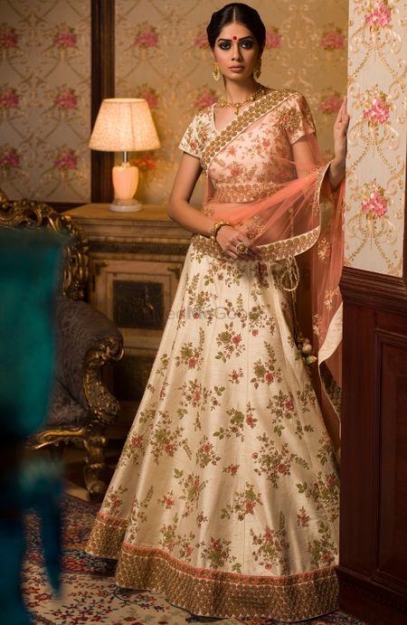 White floral lehenga with gold borders and peach dupatta for mehendi