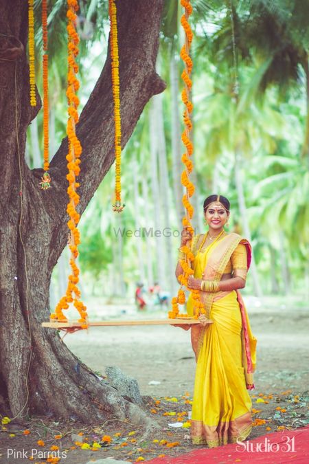 Bright and happy south Indian bride posing with floral swing on wedding day