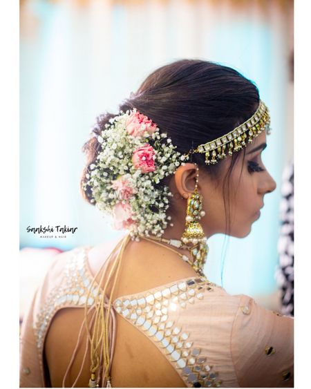 A bride with baby breath and pink roses in her hair on her wedding day 