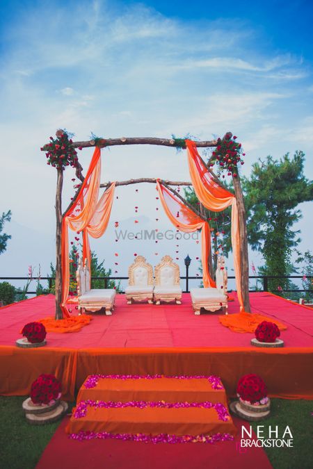 Photo of Orange mandap with sticks and drapes