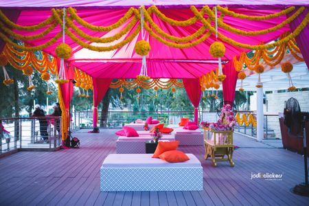 Photo of Simple mehendi decor with pink tenting and marigolds