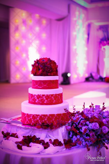 White and red three tier wedding cake with red flowers on top