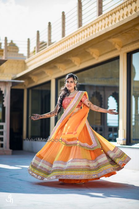 Bride twirling in orange and yellow lehenga