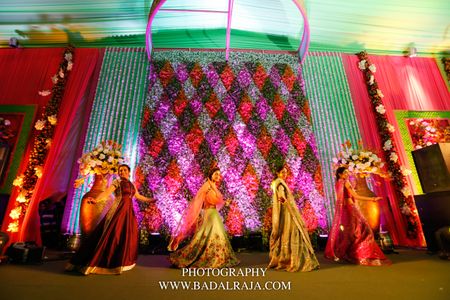 Photo of Bright and colorful floral stage backdrop for sangeet