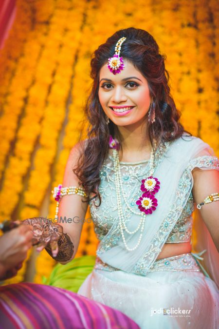 Photo of Bride wearing light blue mehendi and floral jewellery