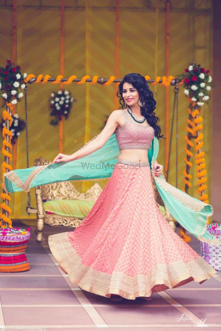 Bride twirling in peach and turquoise lehenga