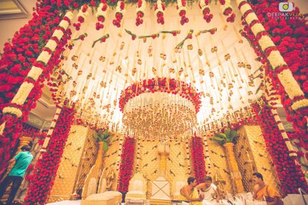 Elaborate red and white mandap with hanging floral strings