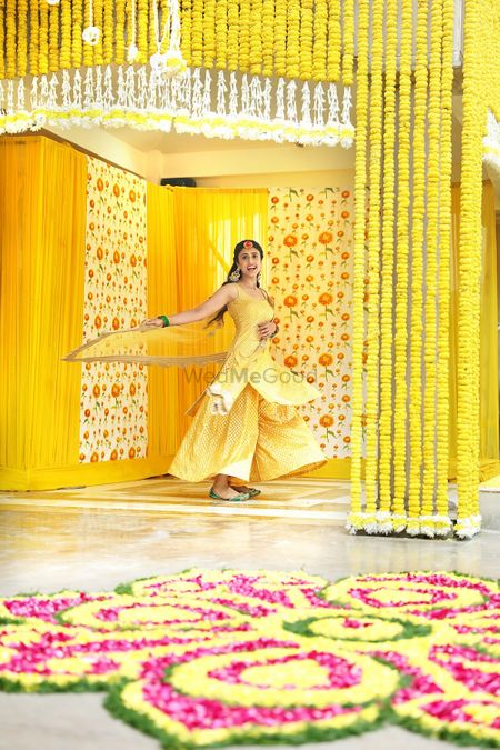 Bride twirling in yellow sharara with bright decor 