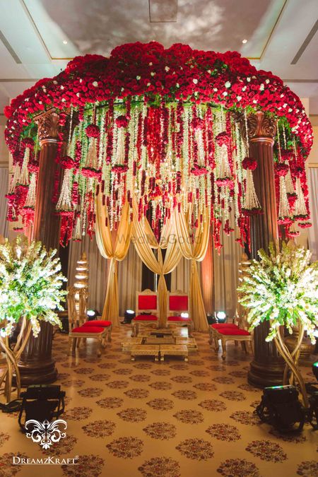 Photo of Floral mandap idea with red and gold decor and hanging strings