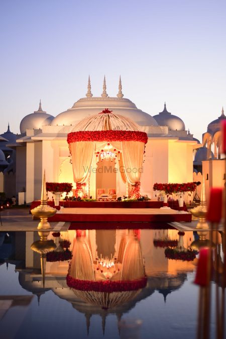 Well lit mandap in red and gold by the water