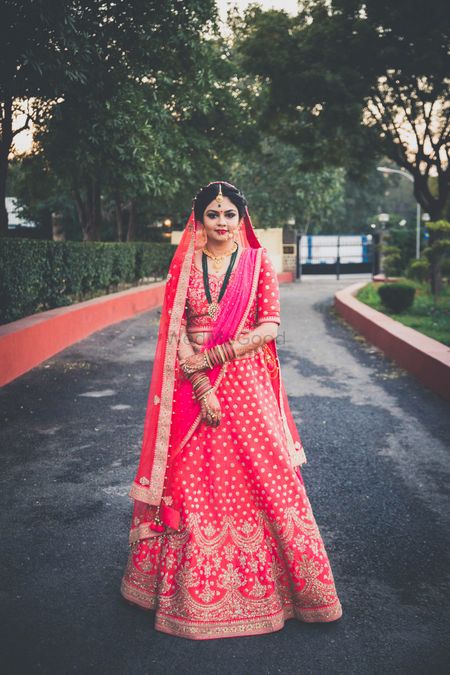 Red and gold bridal lehenga with long green necklace