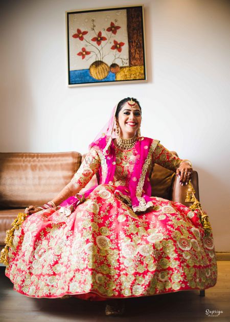 Happy bride in bright pink and gold lehenga