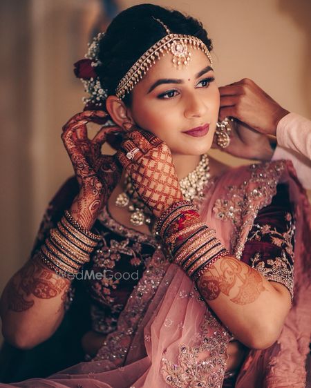 Photo of A bride in a mauve and pink lehenga getting ready