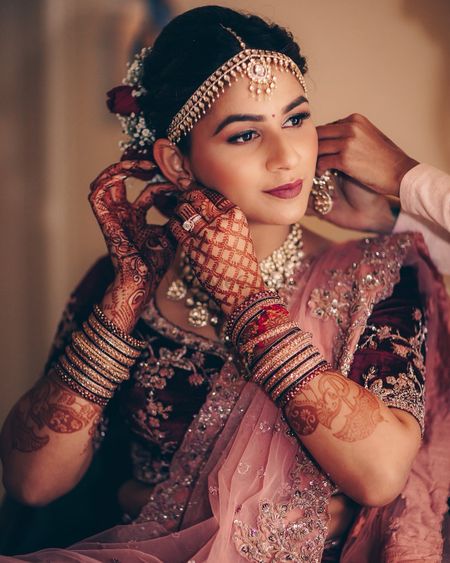 Photo of A bride in a mauve and pink lehenga getting ready