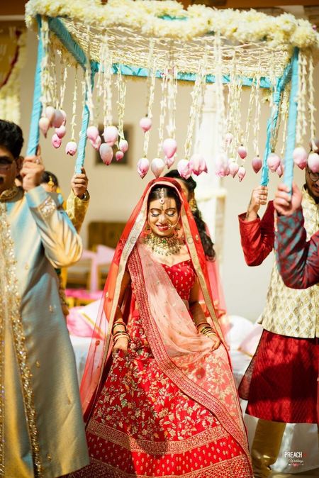 Bride entering under phoolon ki chadar with lotus and floral strings