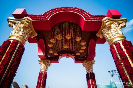 Photo of Traditional red roses laden mandap with brass bells