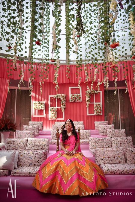 Photo of Mehendi decor with bright pink and hanging floral strings