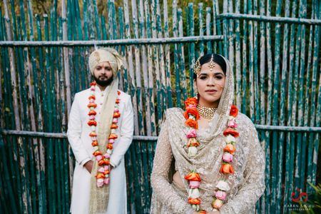 Colourful roses jaimala against ivory bride and groom outfits