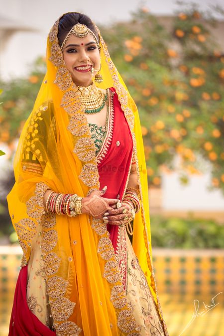 Heavy ivory lehenga skirt with a bright green blouse with double dupatta drape in red and yellow dupattas