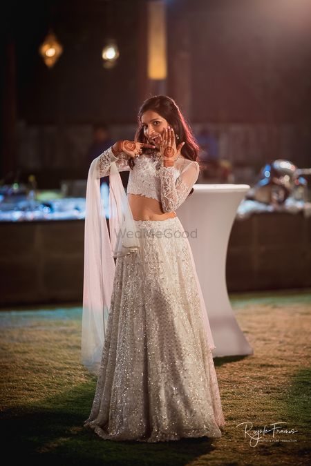 Bride showing off ring in white and gold engagement lehenga 