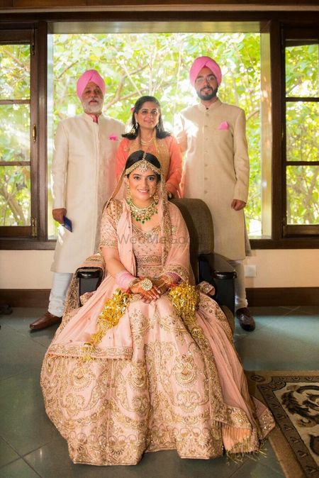 Beautiful family portrait with bride in a peach lehenga and emerald jewellery