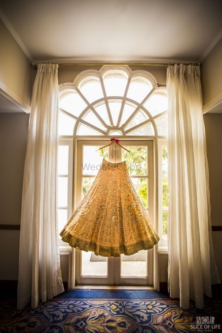 Photo of Peach bridal lehenga on hanger against window