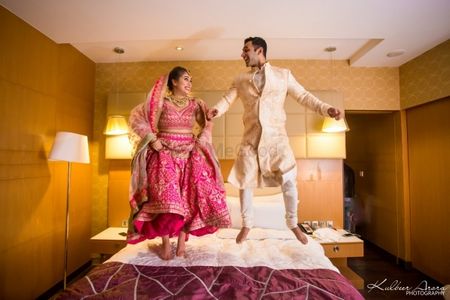 Post wedding shot couple jumping on bed 