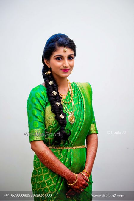 Modern South Indian bride in light green kanjivaram and side braid 