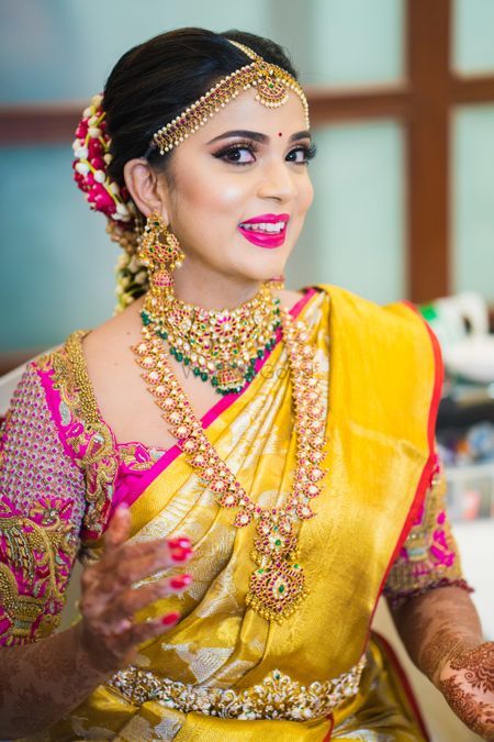 South Indian bridal look with bright pink lips and yellow saree 