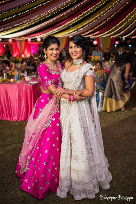 White sangeet lehenga bride with sister in pink 