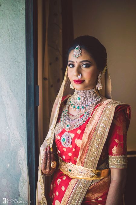 south indian bride in red kanjivaram with contrasting green jewellery