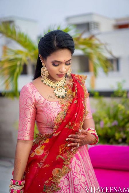 A bride in a pink lehenga with a contrasting dupatta 