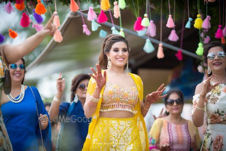 Bride in yellow outfit entering on engagement under tassel chadar