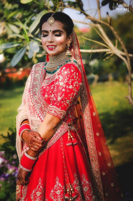 Pretty bridal portrait with red lehenga and emerald jewellery
